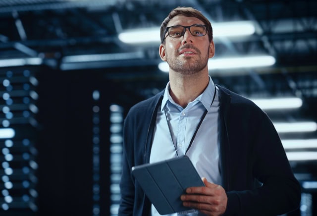 IT specialist walking between rows of hosting servers